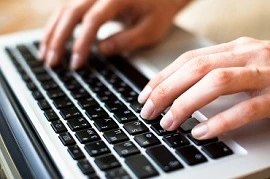 Hands typing on a laptop keyboard for coding